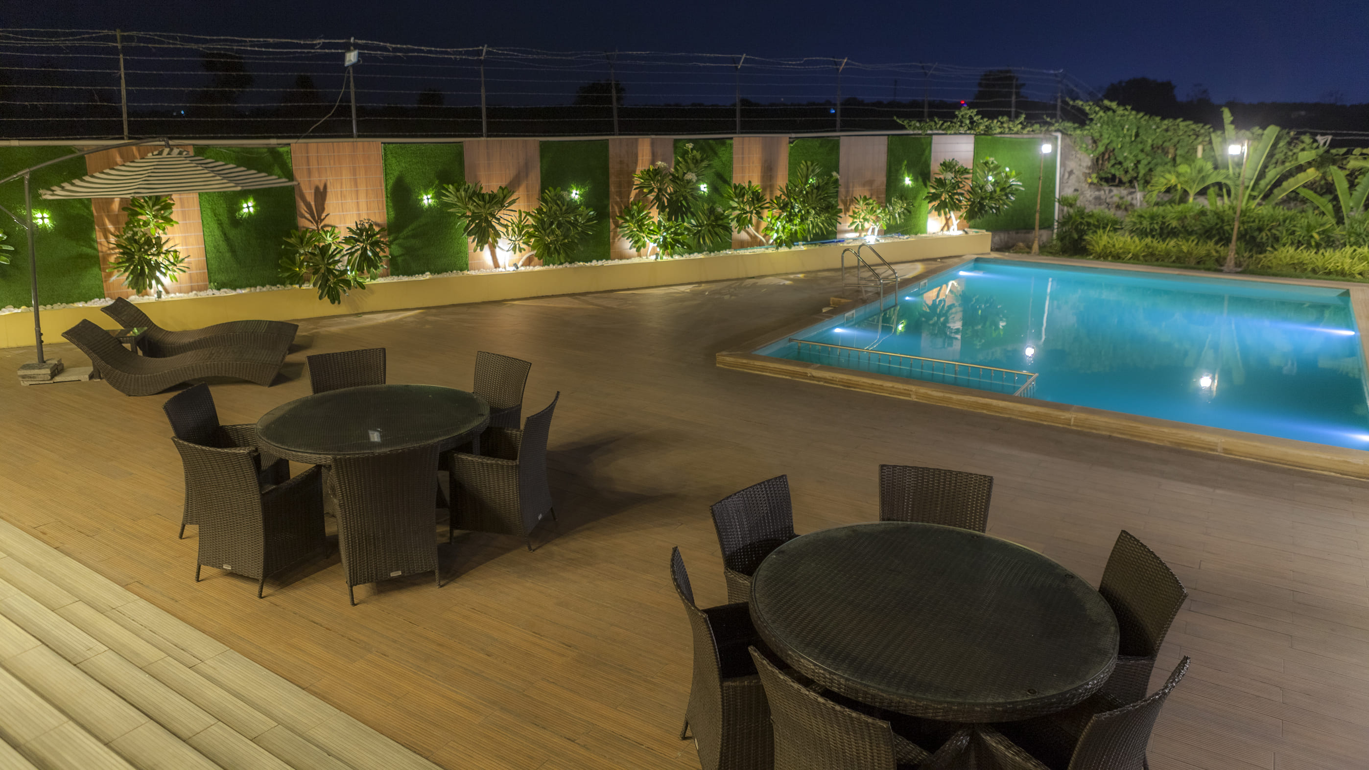Illuminated poolside deck and lounge seating at The Arowana Divine, a villa in Nanded